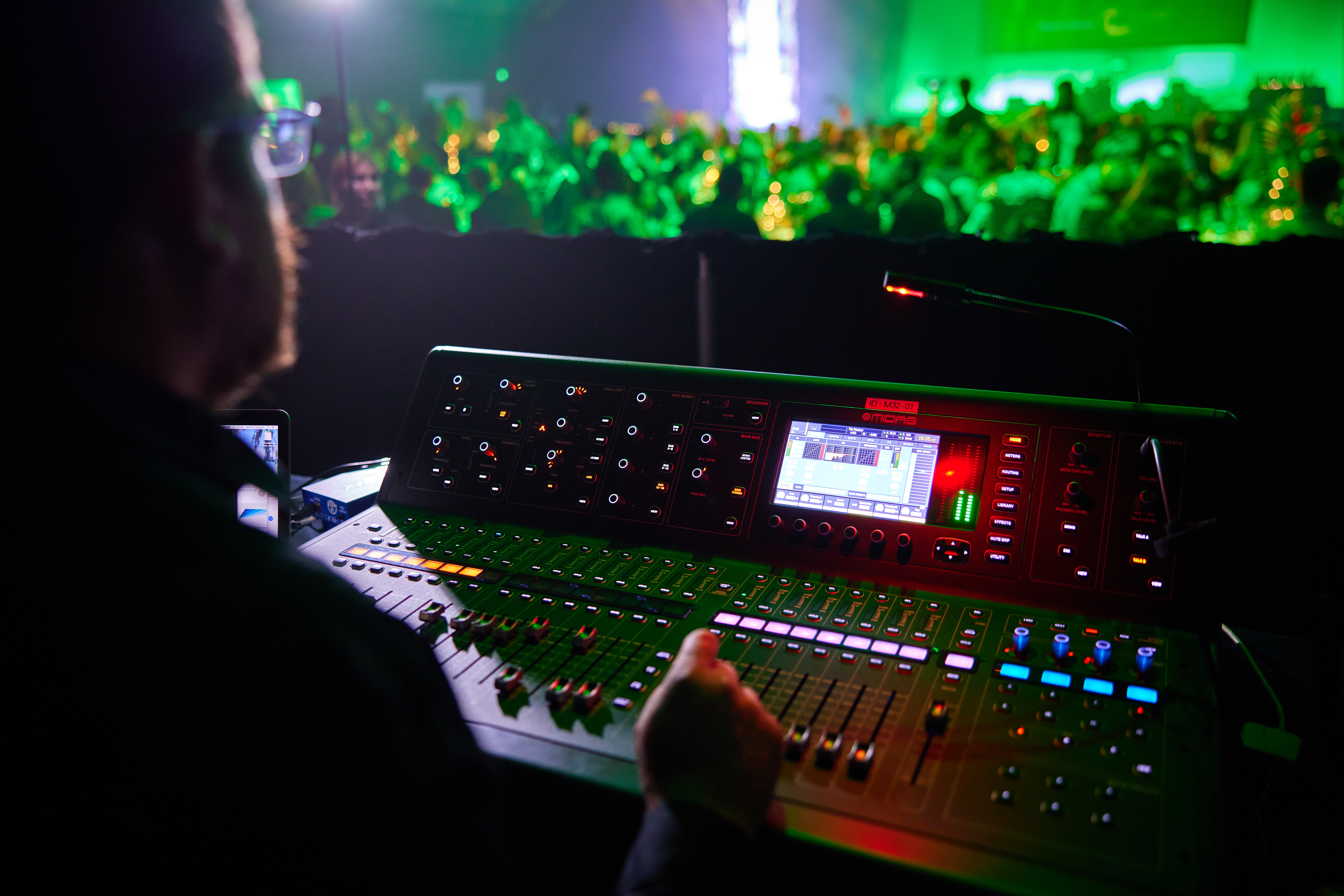 Cairns Convention Centre Staff member operating the sound and audio system with a Gala Dinner in the background. Lots of green lights and people.